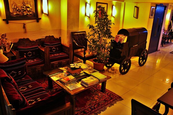 A cozy lounge area with plush seating, a coffee table with books, a potted plant, and a vintage mailbox.