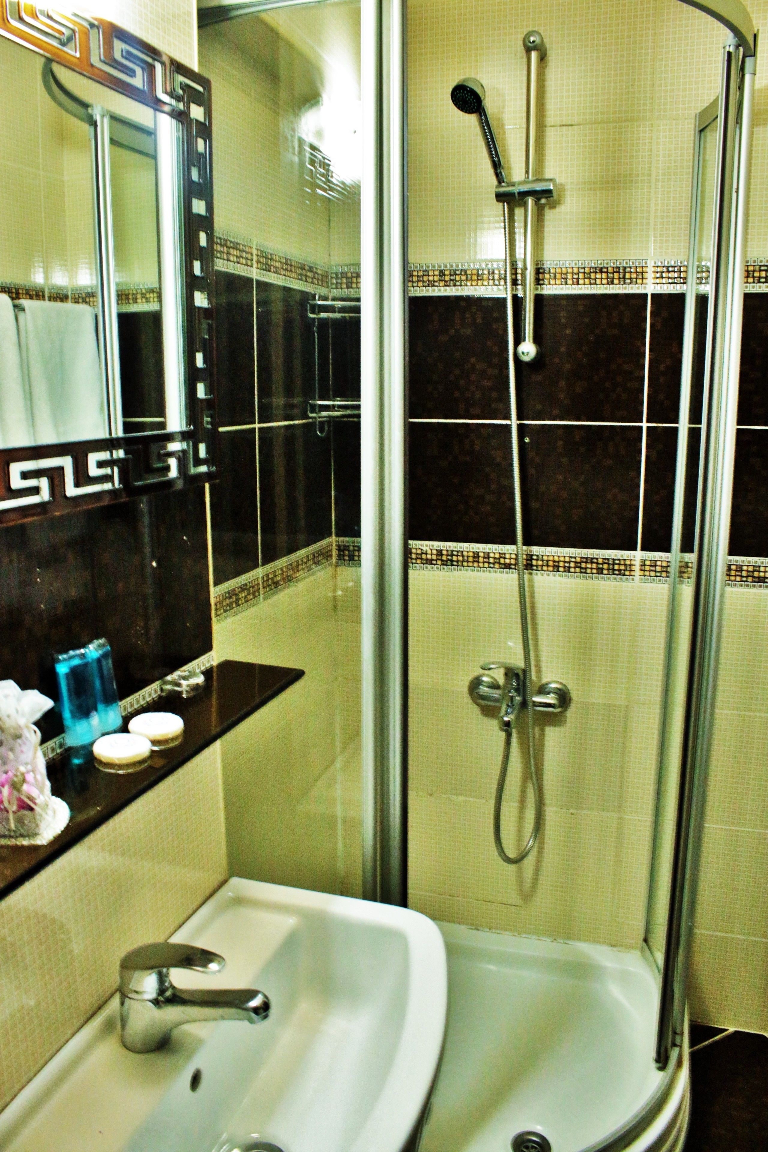 A bathroom with a sink, mirror, and shower.