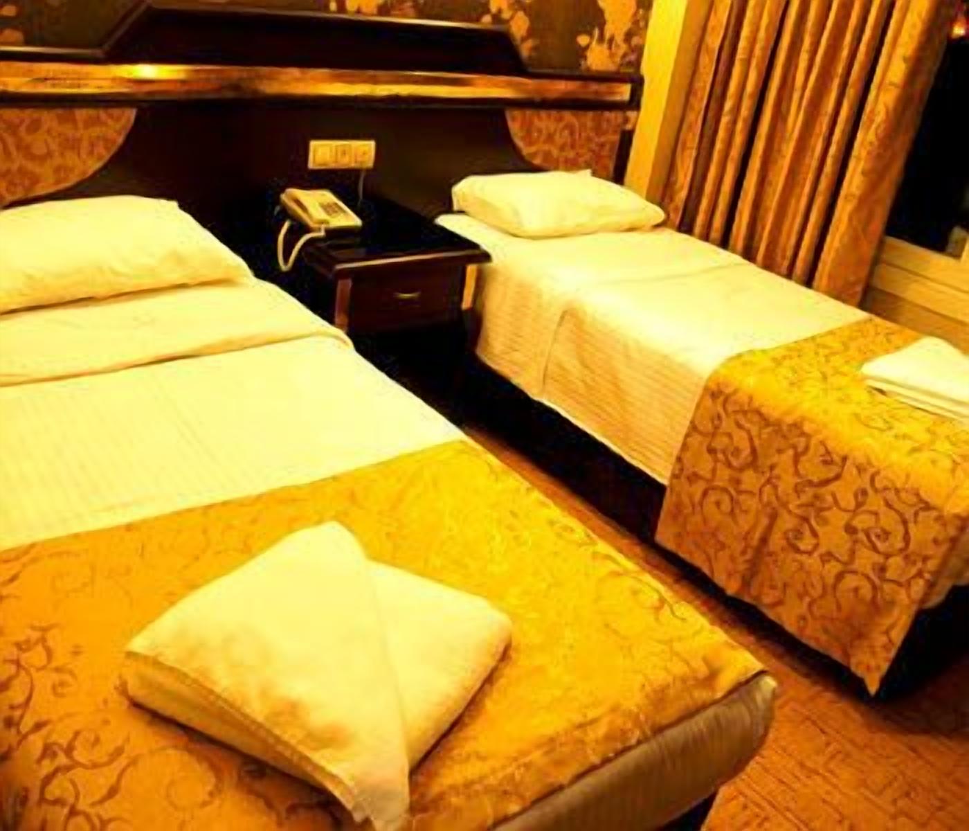 A hotel room with two beds, a bedside telephone, and a nightstand.