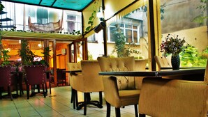 A restaurant with a cozy interior, featuring cushioned chairs and tables, and a view of the outside through large windows. - Sultanahmet Park Hotel (Istanbul)
