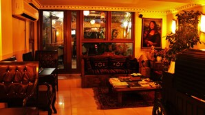 A warmly lit living room with leather furniture, a coffee table, and a large window with a view. - Sultanahmet Park Hotel (Istanbul)