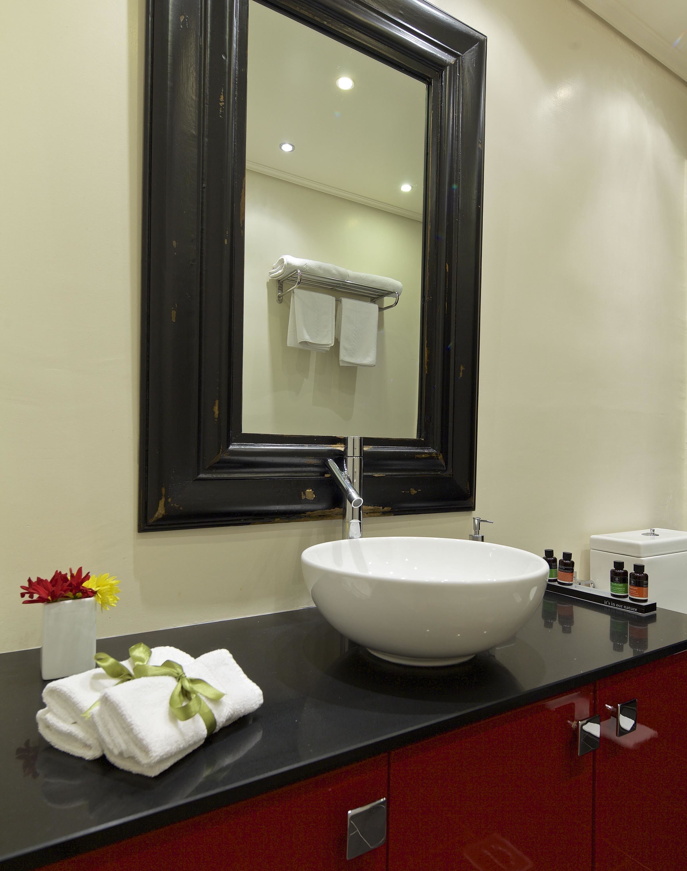 Un baño con un lavabo blanco, un espejo grande y un perchero para toallas.