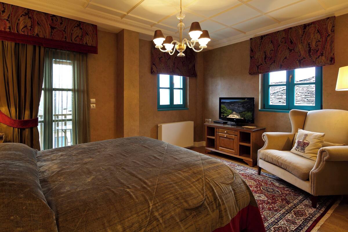Een hotelkamer met een groot bed, een televisie, een bank en een kroonluchter.