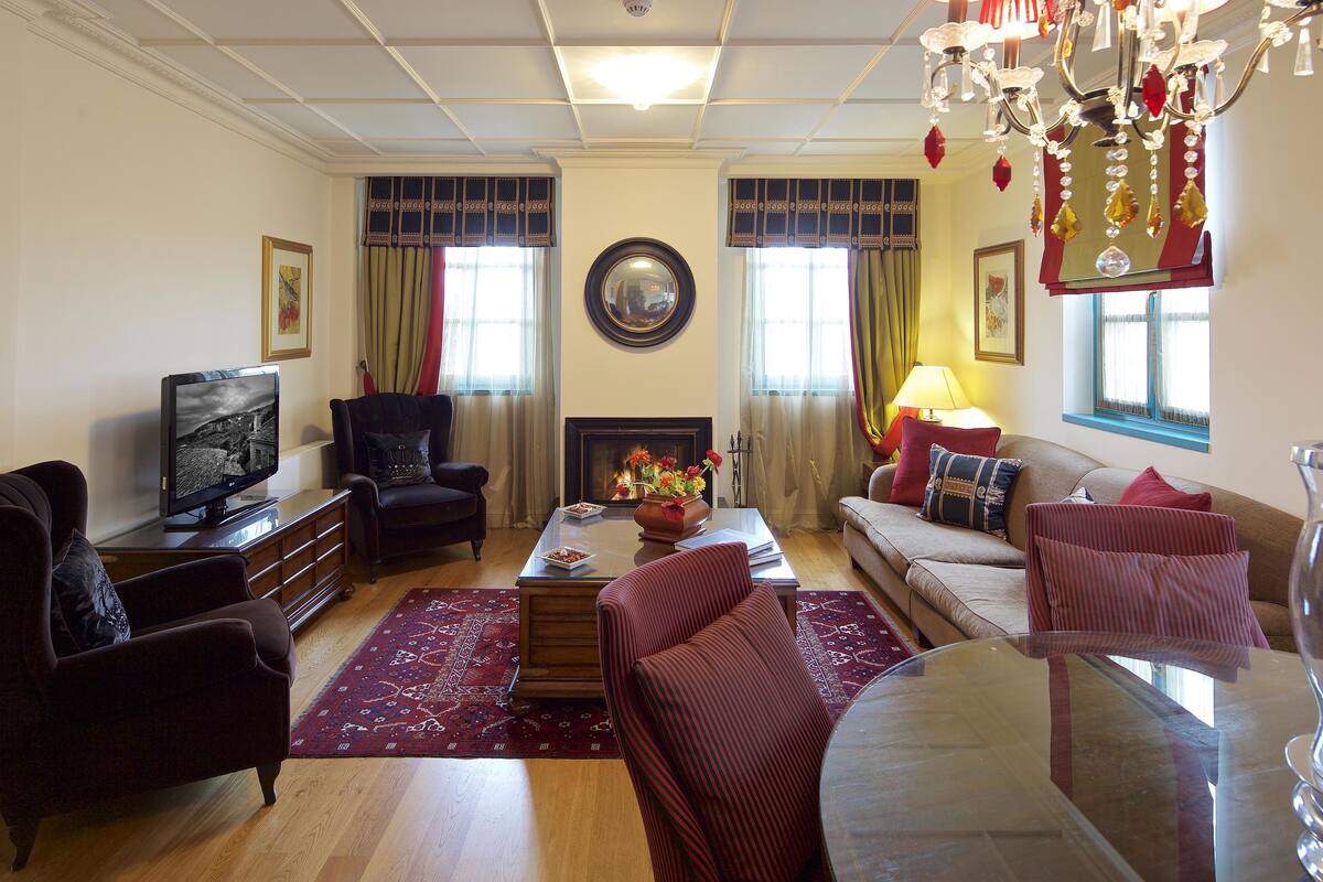 Een woonkamer met een open haard, een televisie en een kroonluchter.