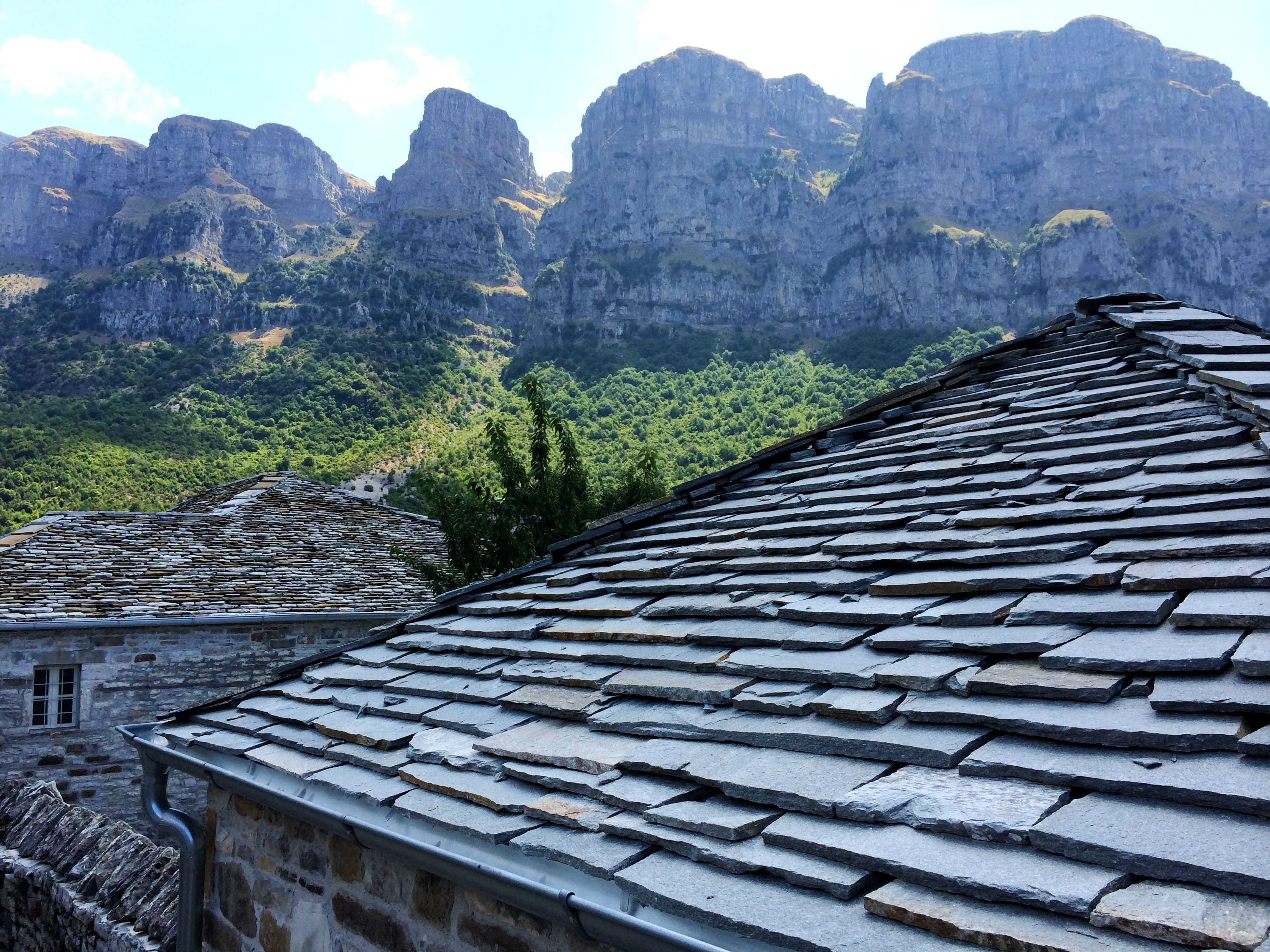 Un bâtiment doté d’un toit en pierre, offrant une vue sur un paysage montagneux.