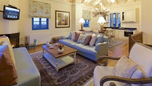 Een woonkamer met een bank, fauteuils, een salontafel en een televisie.