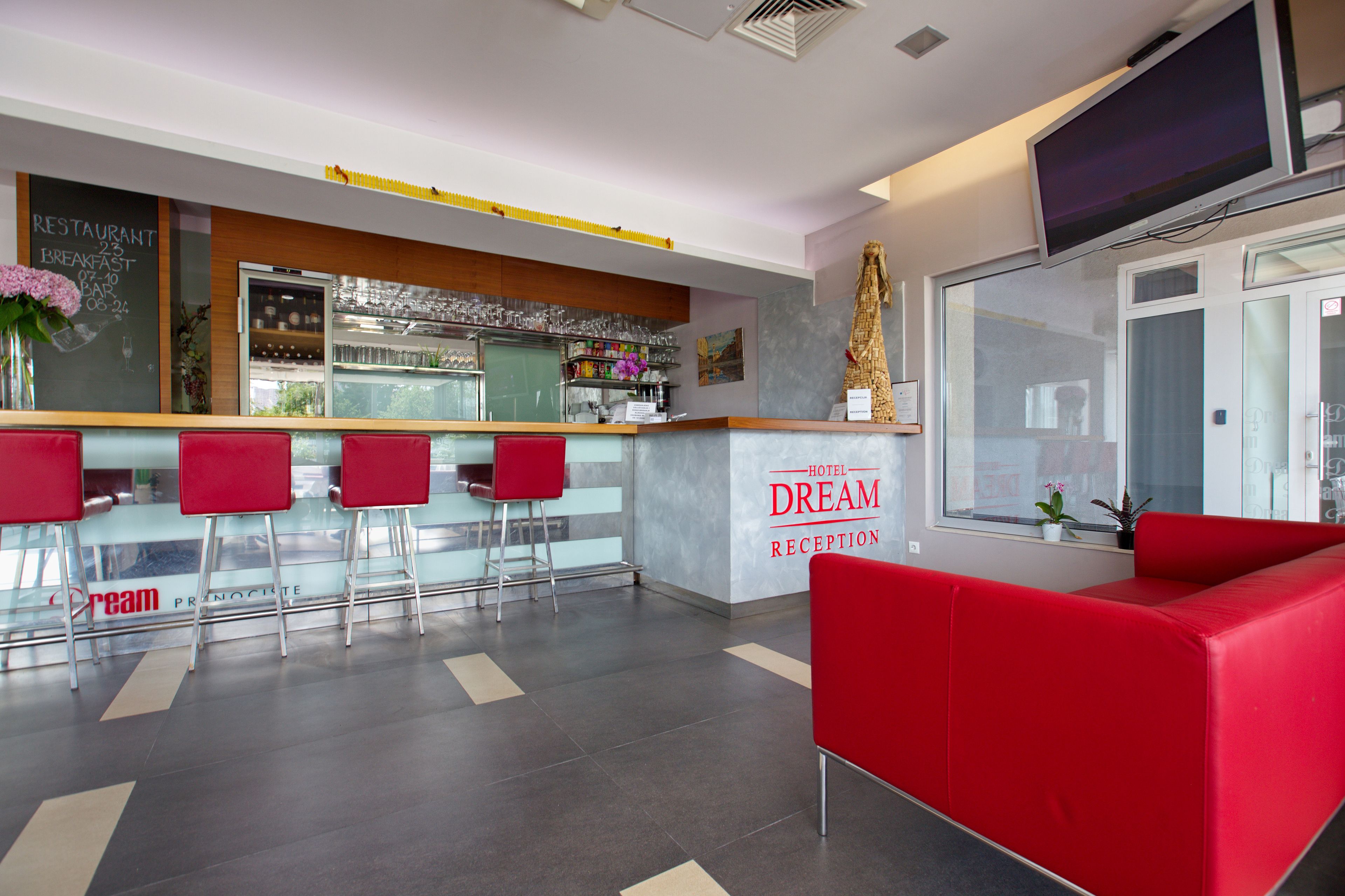 A hotel reception area with a bar, red seating, and a large window.
