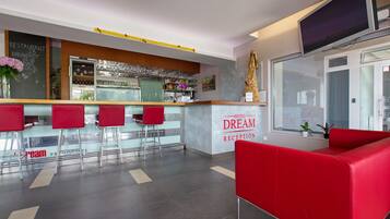 A hotel reception area with a bar, red seating, and a large window.
