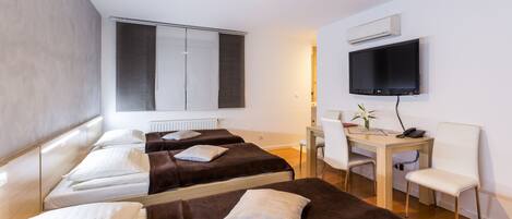 Une chambre d’hôtel avec deux lits, un bureau, une chaise, une télévision et un appareil de climatisation.
