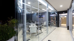 Un interior moderno con paredes de vidrio, una recepción y una zona de estar con mesas y sillas.