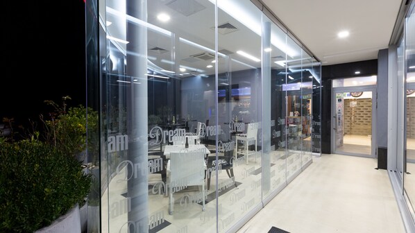 A modern interior with glass walls, a reception desk, and a seating area with tables and chairs.