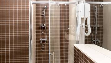 Uma área de chuveiro moderna com divisória de vidro, chuveiro manual e chuveiro fixo na parede, além de um chuveiro manual com mangueira flexível.