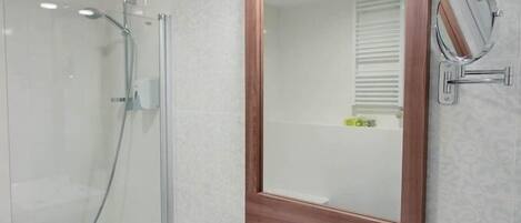 A modern bathroom with a glass-enclosed shower, a white sink with a wooden vanity, and a large mirror with lights.