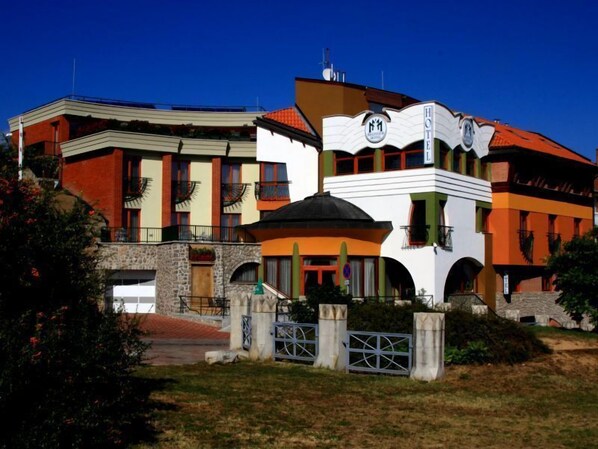 A hotel with a modern architectural design, featuring a mix of brick and stucco exteriors, multiple balconies, and a prominent logo on the facade.