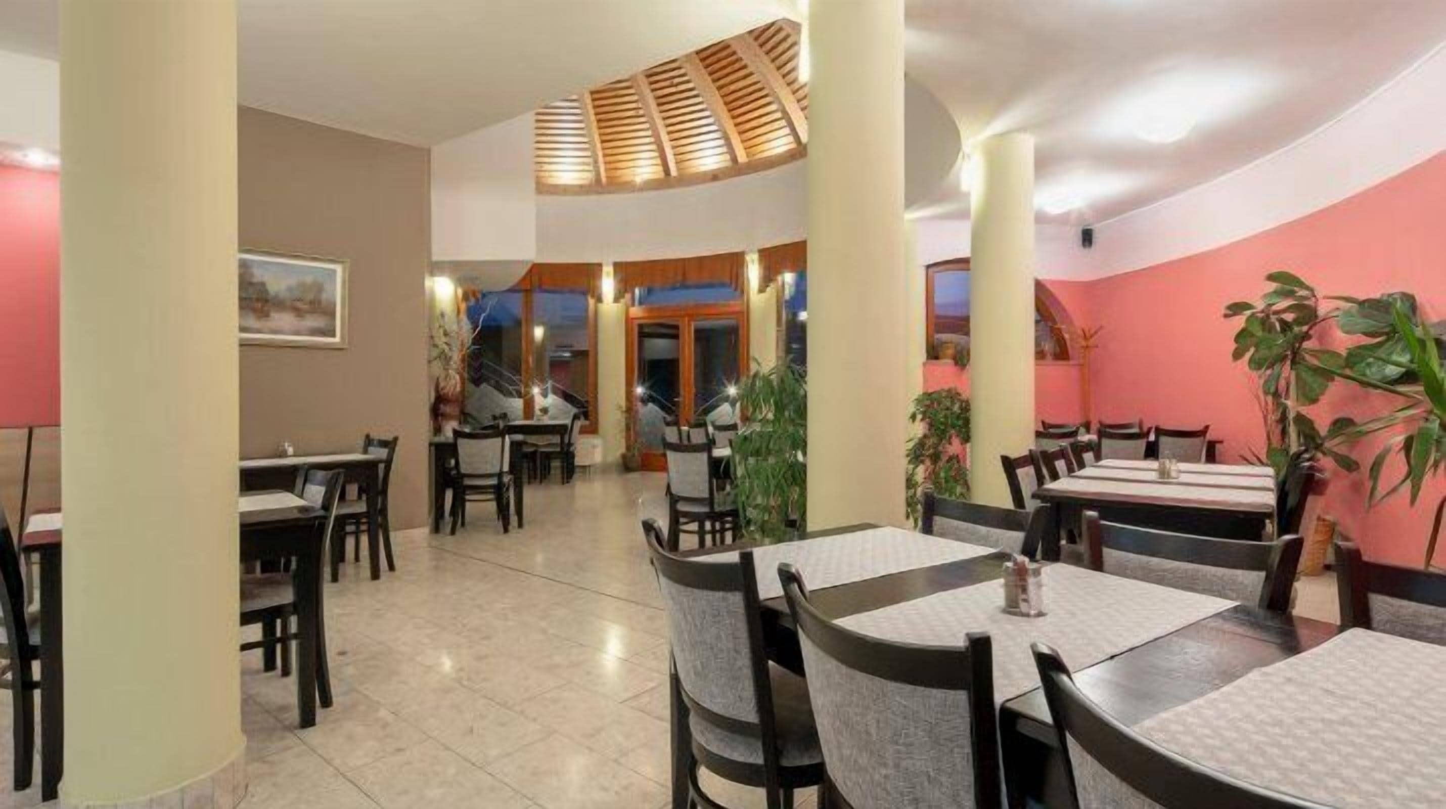 Un restaurante con varias mesas y sillas, un espacio central abierto y vista a la calle.