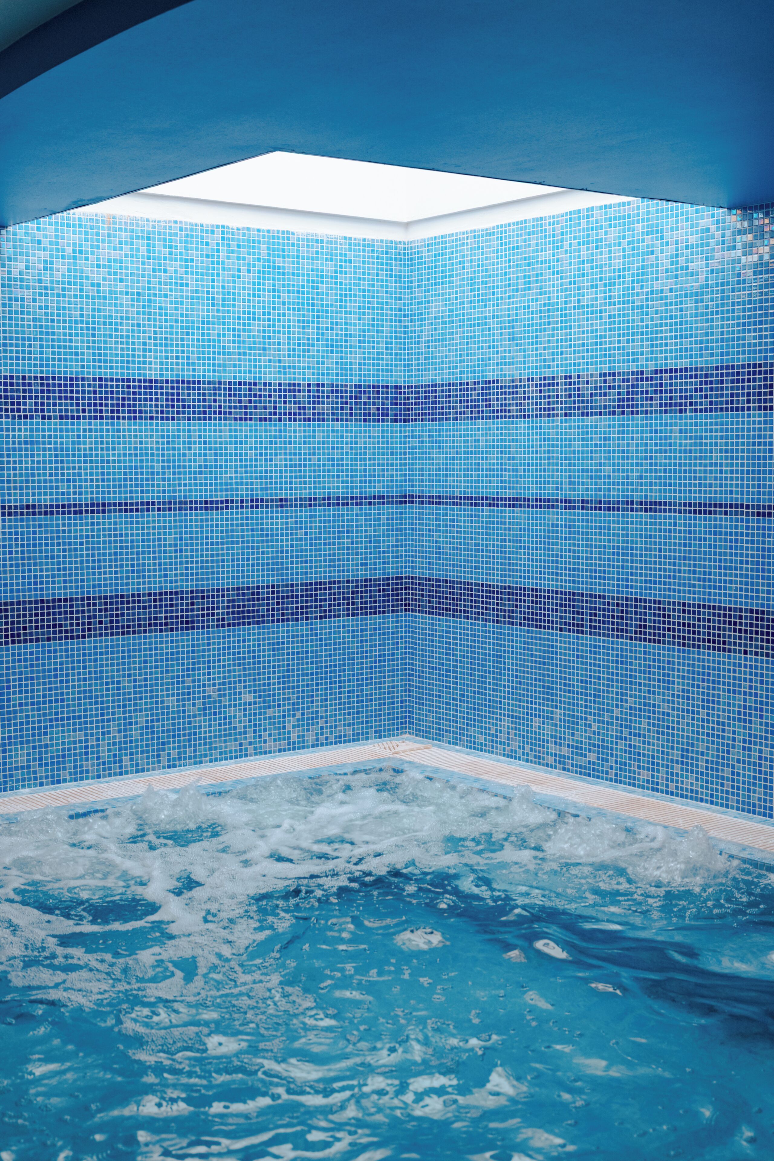 A swimming pool with a tiled wall and a clear view of the sky.