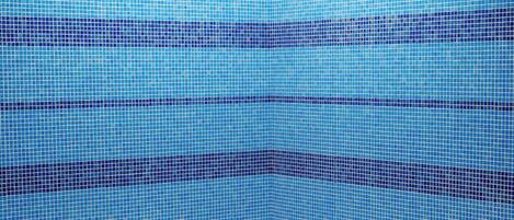 A swimming pool with a tiled wall and a clear view of the sky.