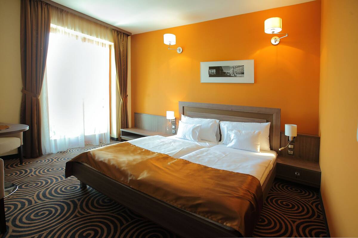 A hotel room with a large bed, two bedside tables, a desk, and a chair.