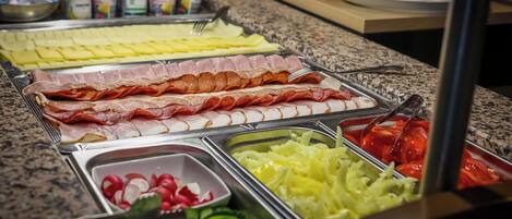 Un bufé con diversas opciones de comida, incluyendo carnes, quesos y verduras frescas.
