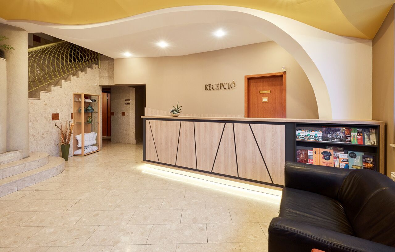 Zona de recepción con mostrador, escalera y área de descanso.