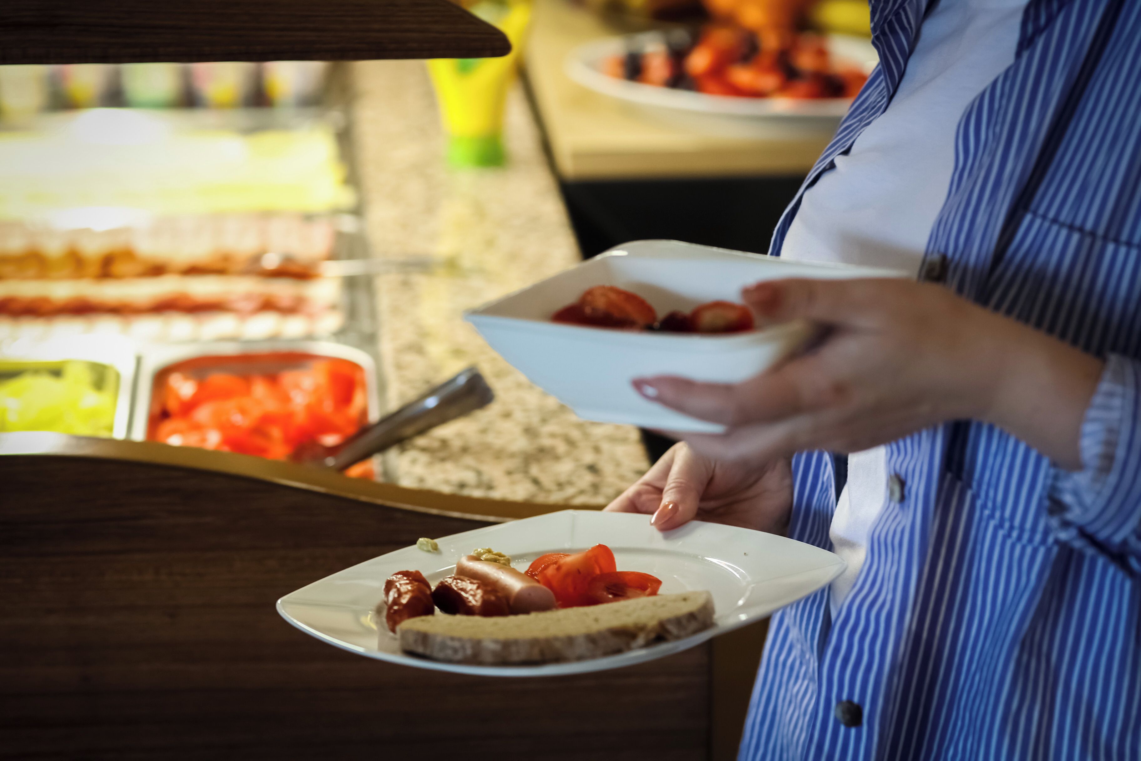 Una persona serve cibo da un buffet.