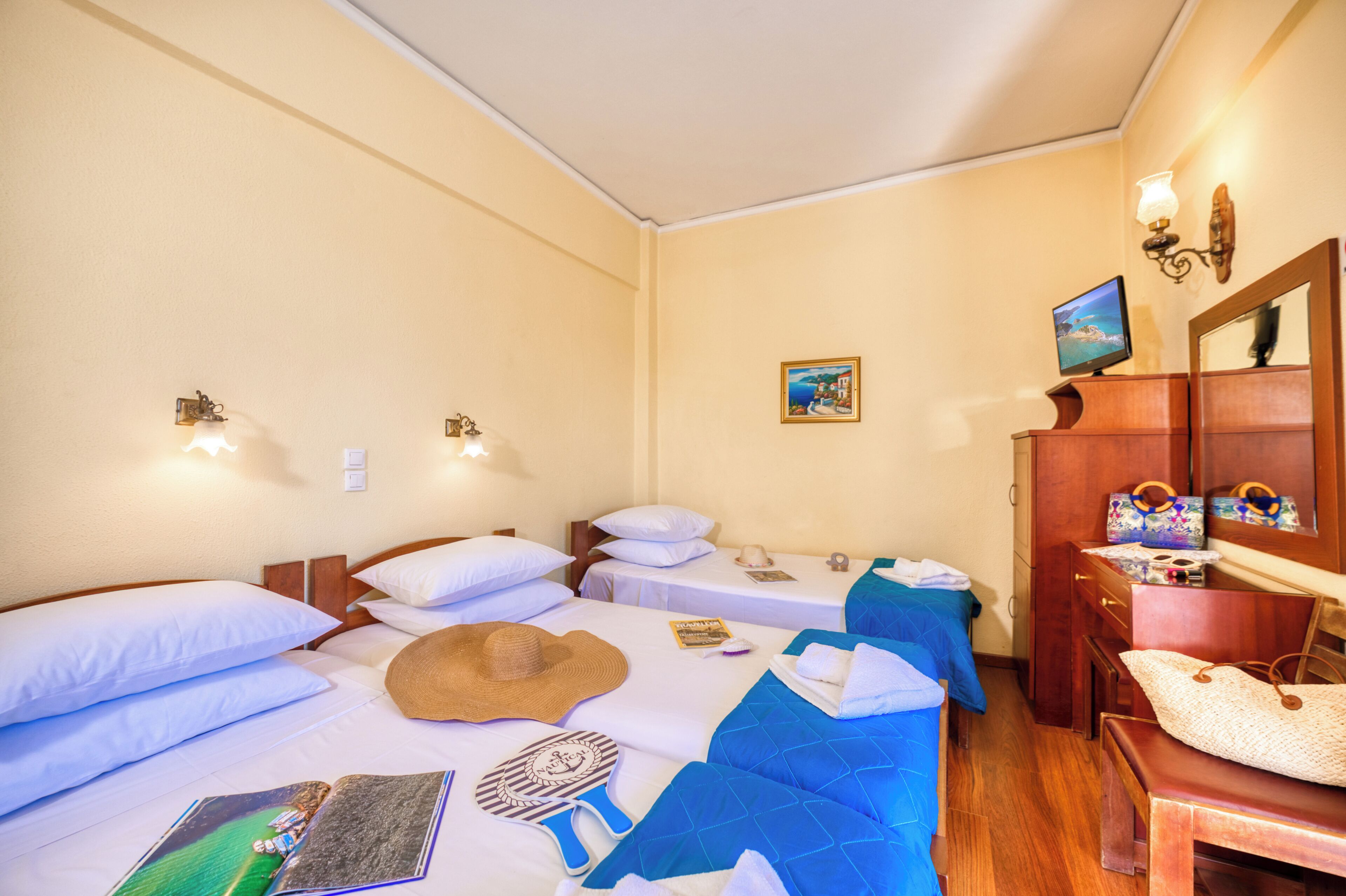 A hotel room with two beds, a wooden dresser, a mirror, a wall-mounted TV, and a painting.