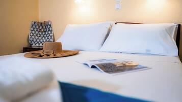 A neatly made bed with white linens, a wooden headboard, and a magazine on the bed.