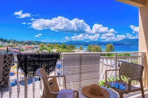 A balcony with wicker chairs, a table with a hat, and a striped towel.