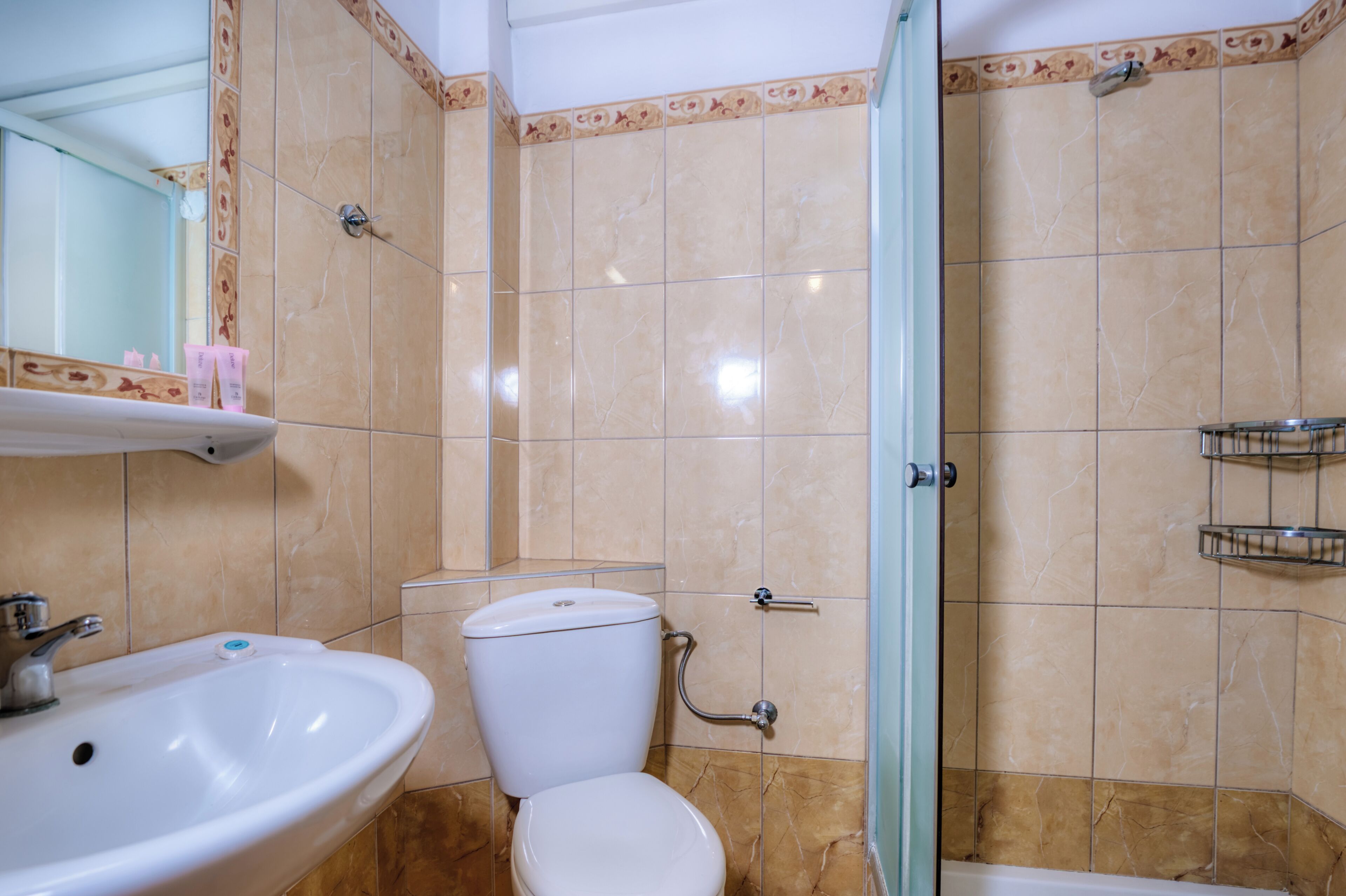A bathroom with a toilet, sink, shower, and tiled walls.