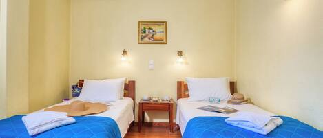 A hotel room with two beds, a nightstand, a wall-mounted air conditioner, and a painting.