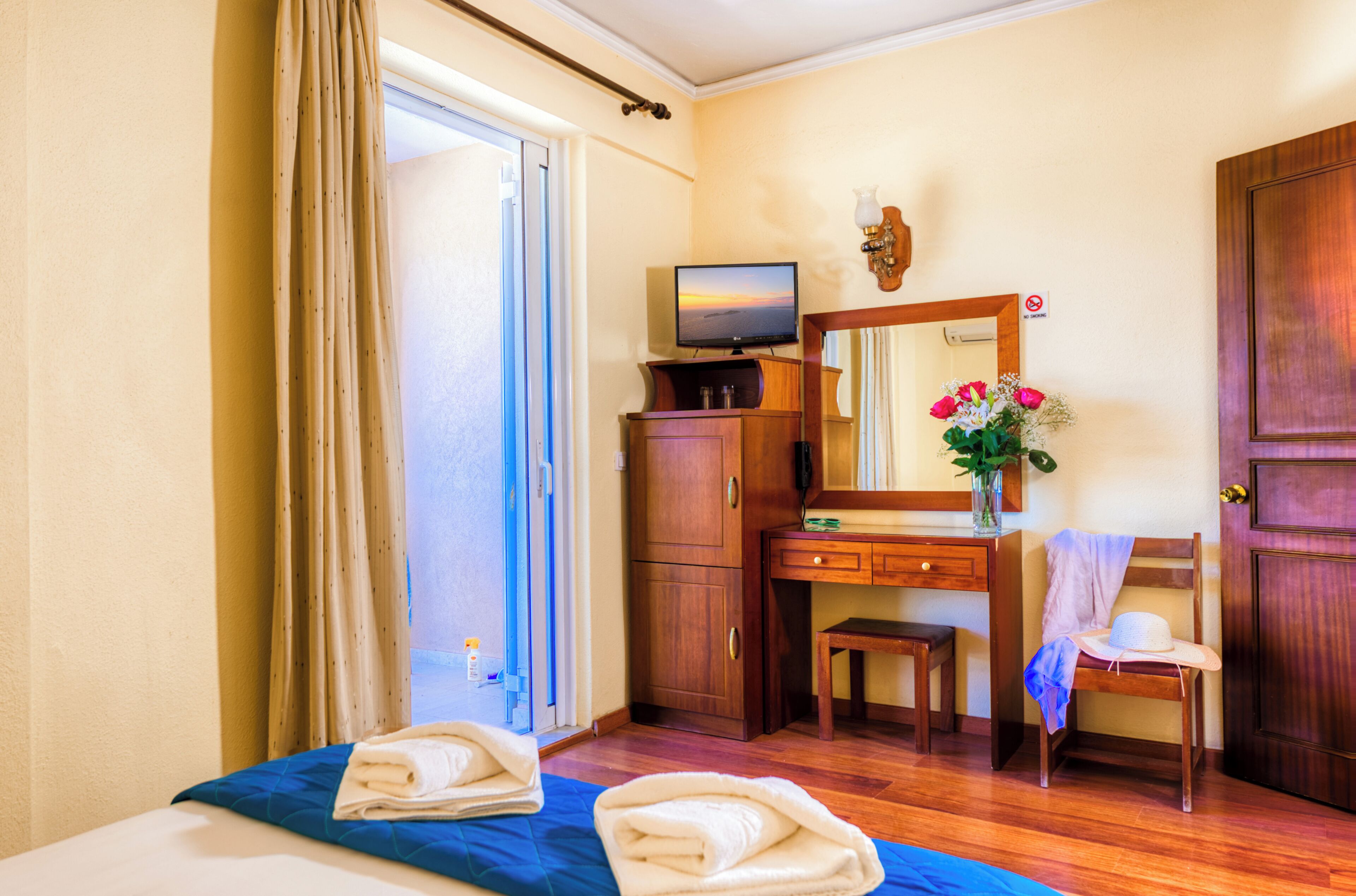 Habitació d'hotel amb un llit, escriptori, televisió, mirall i porta.