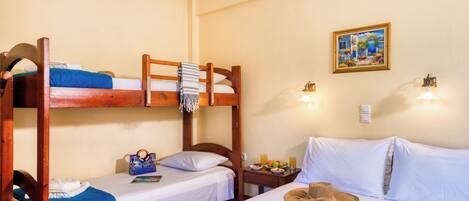 A room with bunk beds, a bedside table with a hat, a magazine, and a fruit plate.