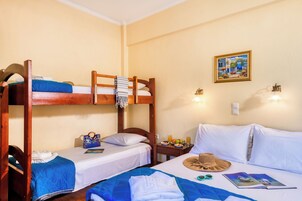 A room with bunk beds, a bedside table with a hat, a magazine, and a fruit plate.