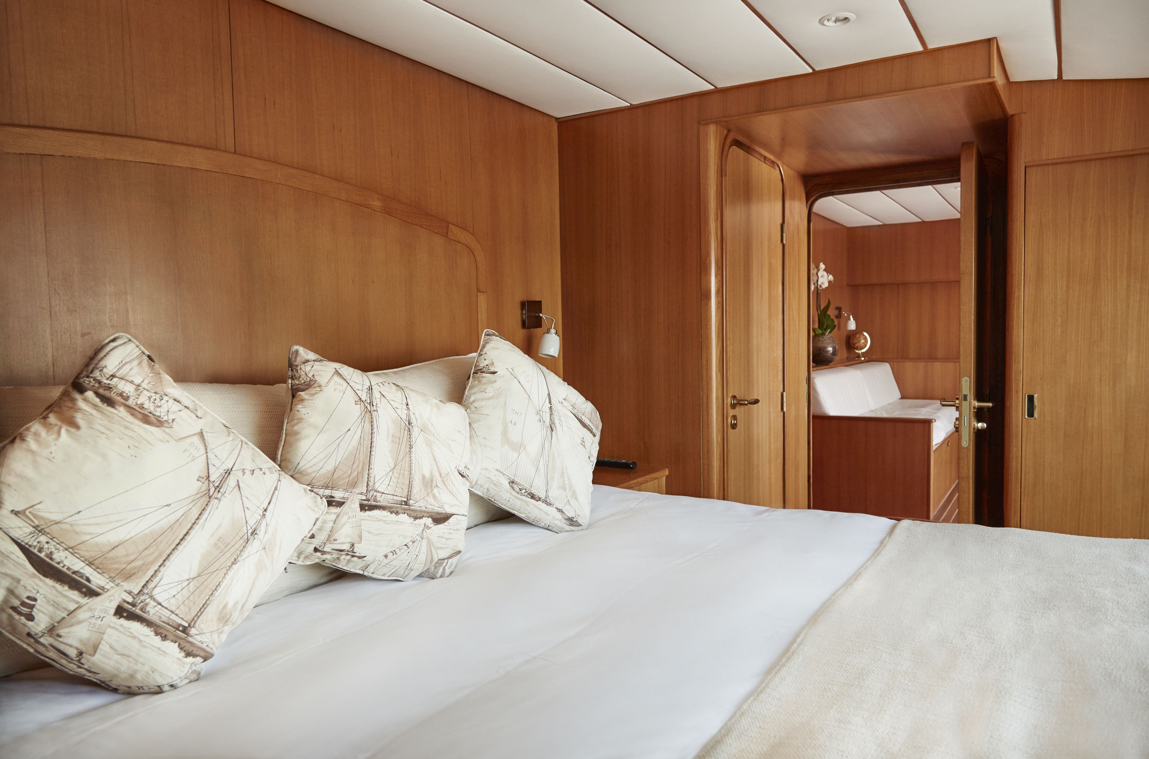 Una habitación con paneles de madera, una cama, una mesita de noche y una puerta de madera que da a un baño.