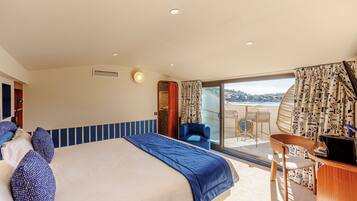 A hotel room with a bed, a desk, a chair, and a balcony with a view.