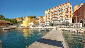 A waterfront hotel with a dock, boats, and a clear blue sky. - Welcome Hôtel (Villefranche-sur-Mer)