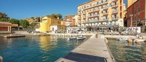 A waterfront hotel with a dock, boats, and a clear blue sky.