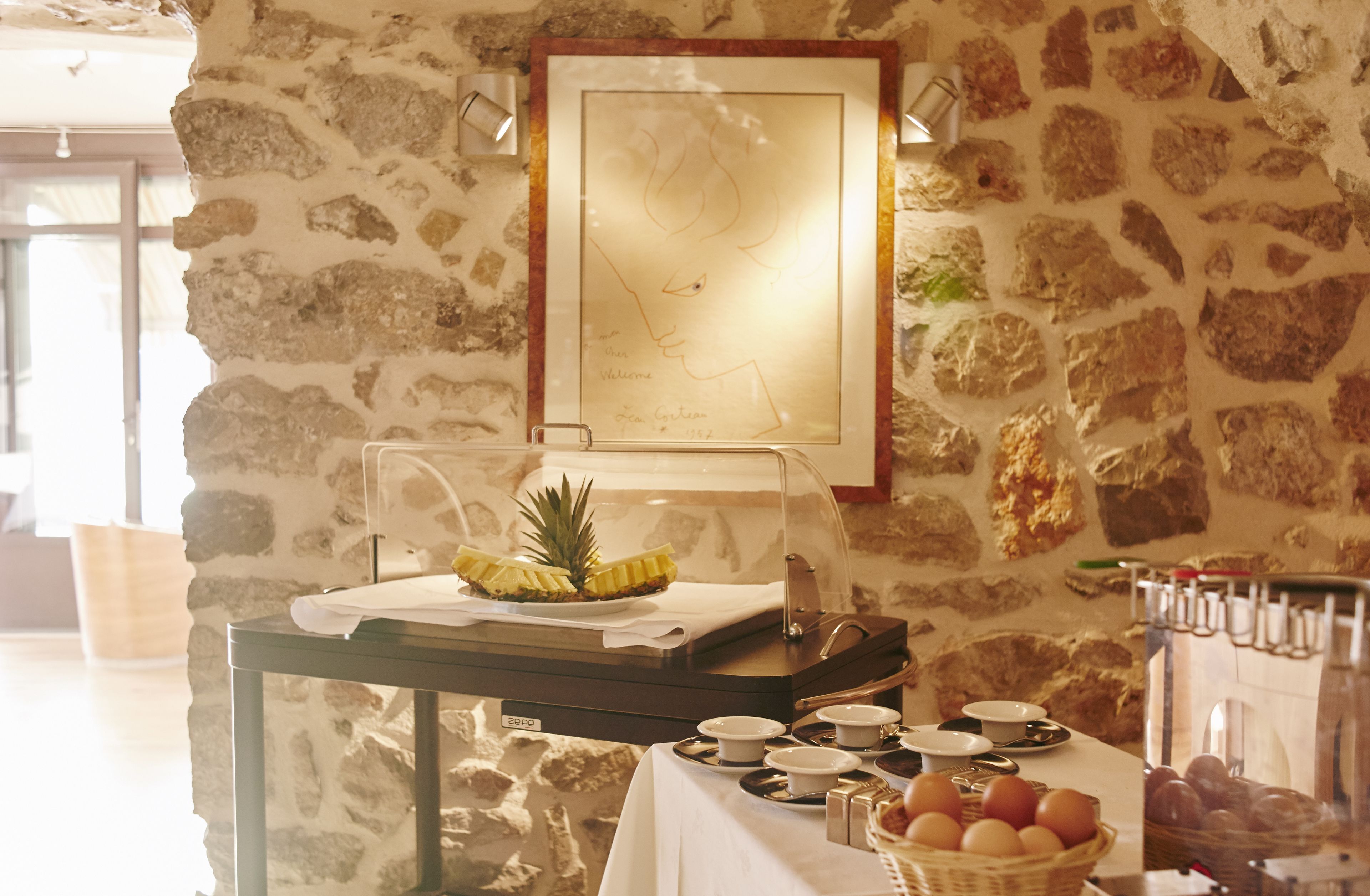 A breakfast buffet setup with a tropical fruit display, a framed map, and various breakfast items on a table.