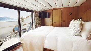 A bedroom with a large bed, a TV mounted on the wall, and a view of the outdoors.