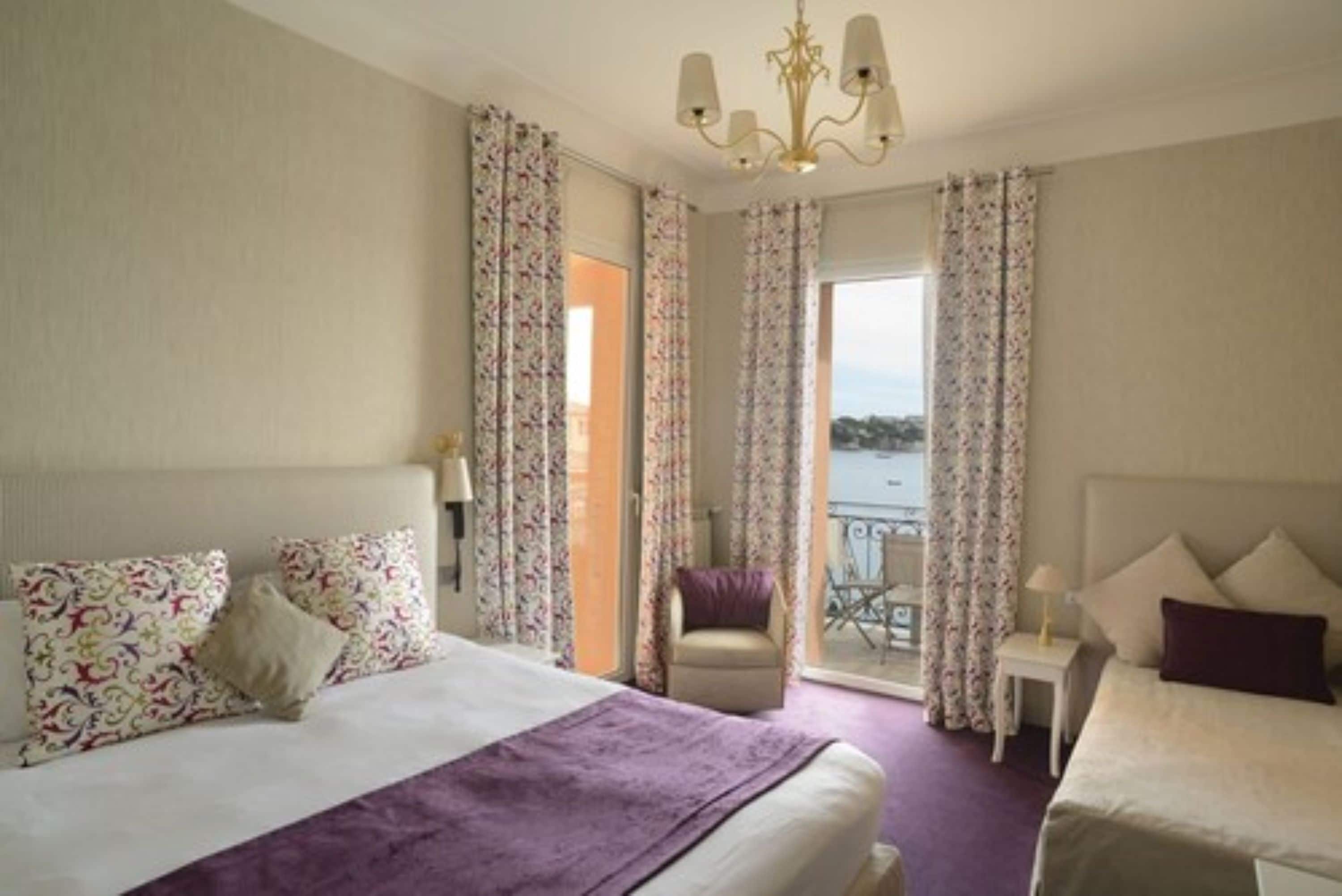 Una habitación de hotel con cama, una silla, una mesita y vista al mar.