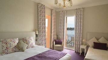 Una habitación de hotel con cama, una silla, una mesita y vista al mar.