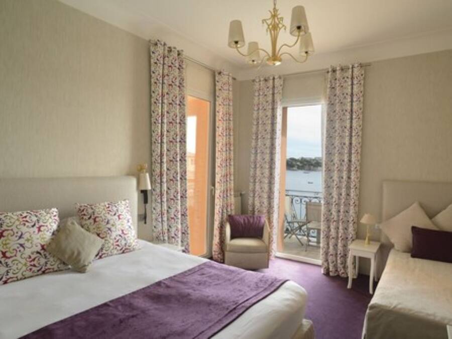 Una habitación de hotel con cama, una silla, una mesita y vista al mar.
