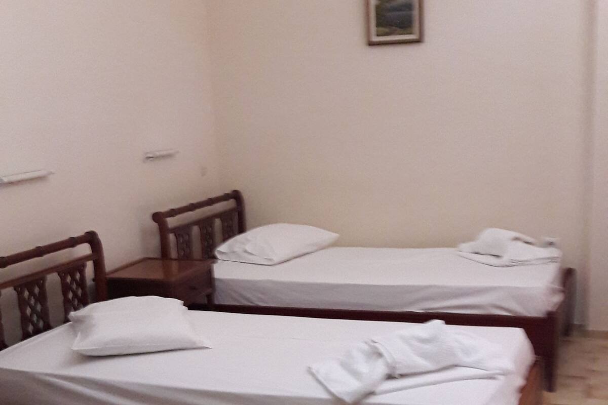 A room with two wooden beds, a wooden chair, and a small table.