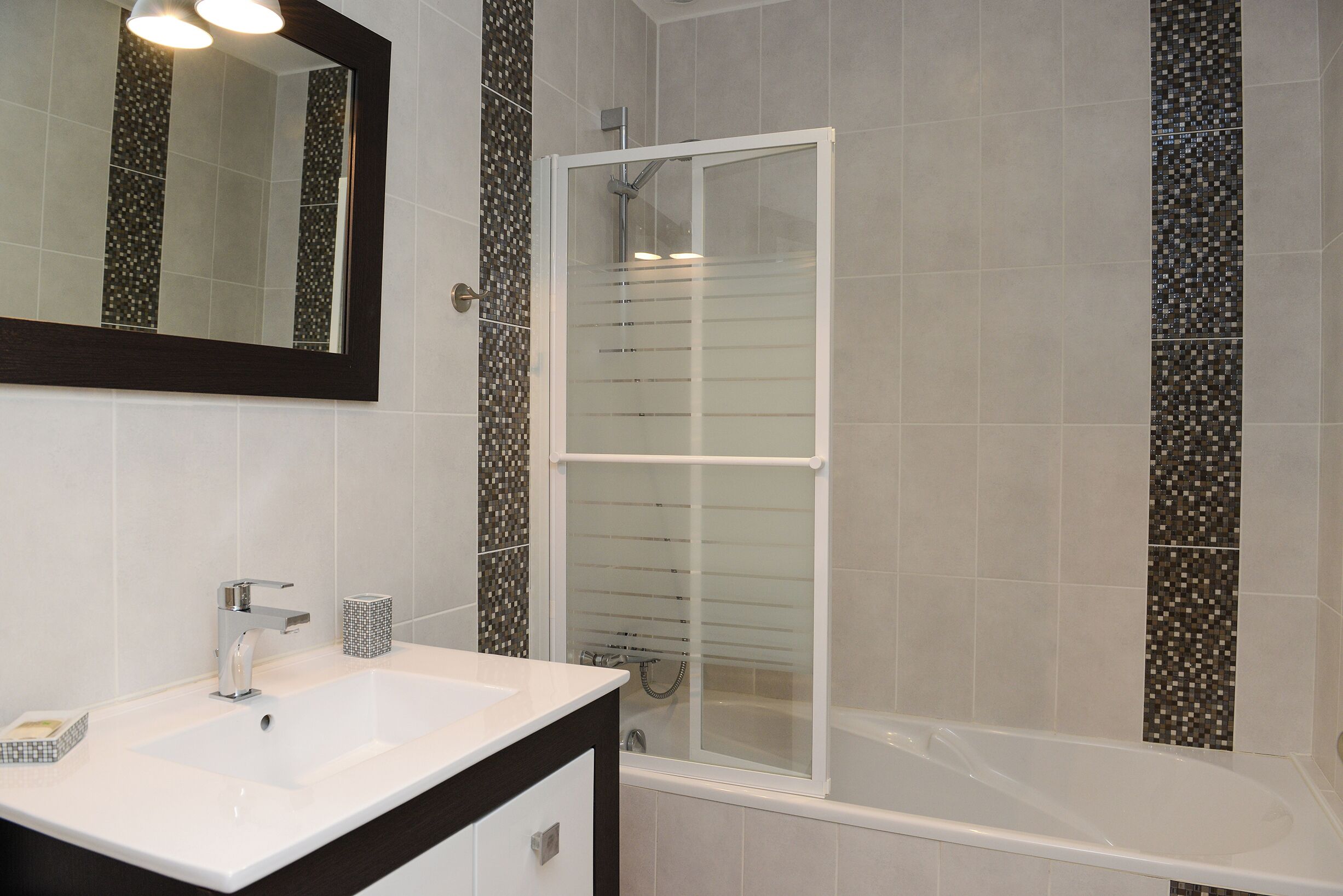 Een moderne badkamer met een wit wastafelmeubel, een spiegel en een douche met glazen wanden.