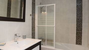 Een moderne badkamer met een wit wastafelmeubel, een spiegel en een douche met glazen wanden.