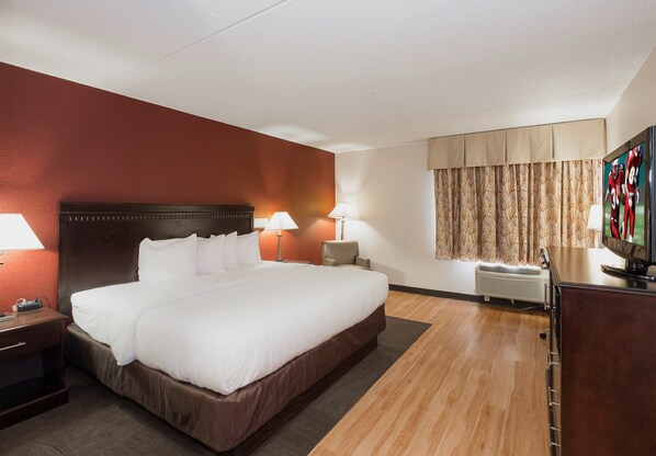 Habitación de hotel con una cama grande, dos lámparas de noche, un televisor y una ventana con cortinas.