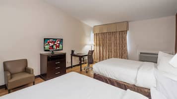 Quarto de hotel com duas camas, uma mesa, uma cadeira, uma televisão e uma janela com cortinas.