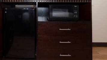 A kitchenette with a refrigerator, microwave, and a television on top.