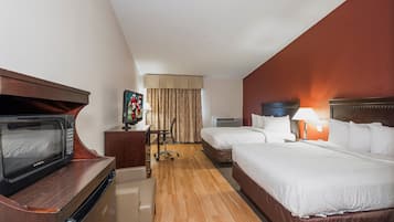 A hotel room with a microwave, a television, two beds, a desk, a chair, and a window with curtains.