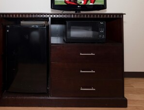 Una kitchenette con un refrigerador negro, un microondas y un televisor de pantalla plana encima.
